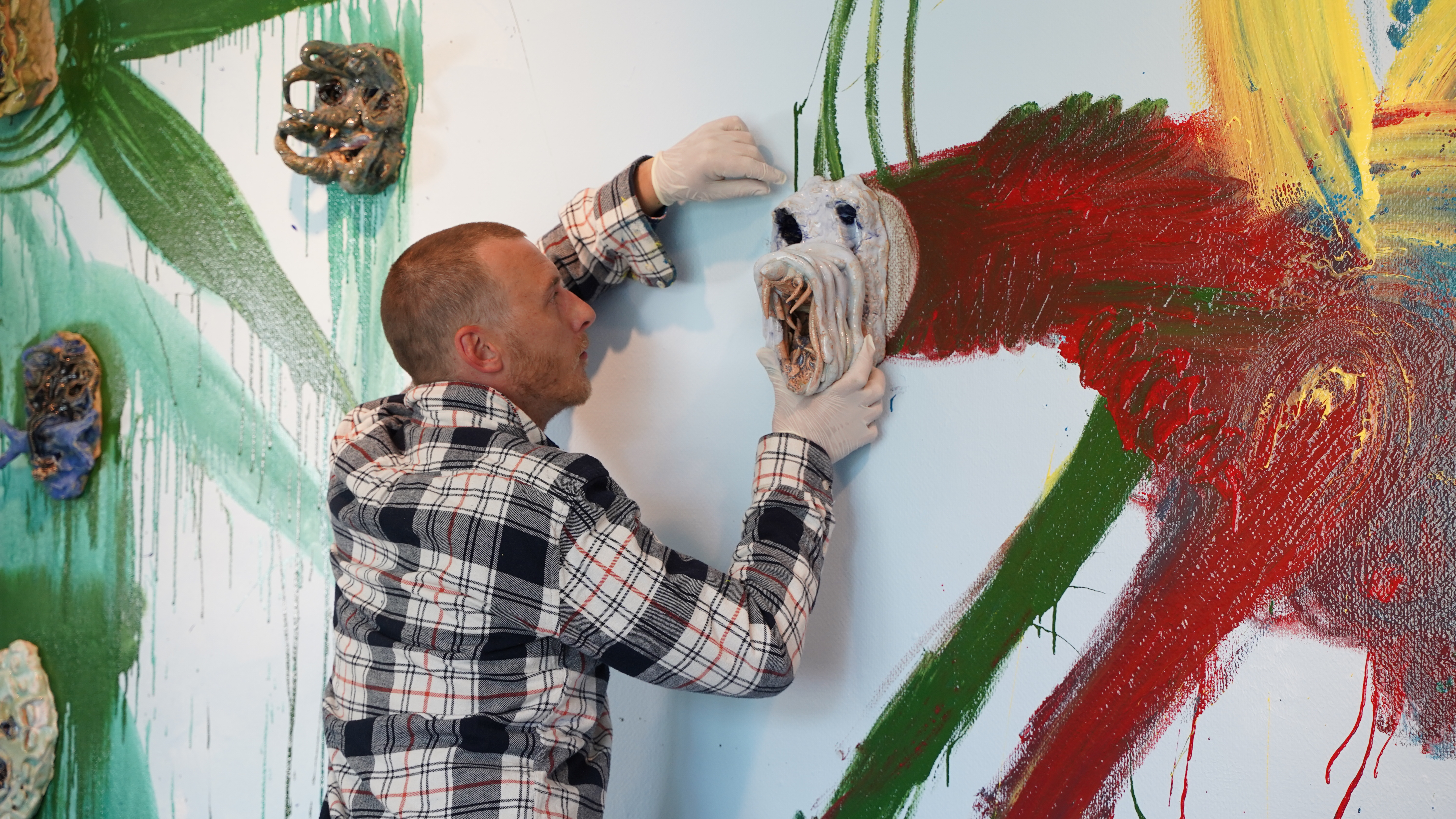 Næblerød monterer maske på vægmaleri