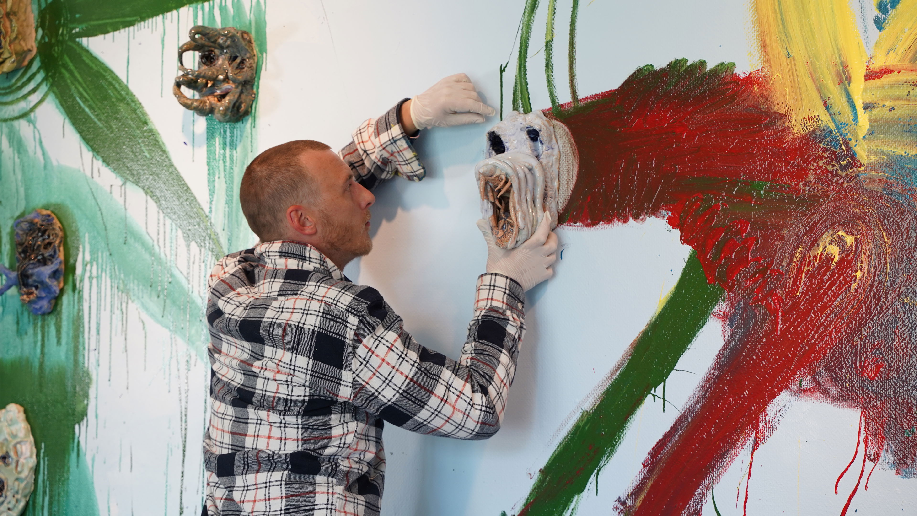 Næblerød monterer maske på vægmaleri